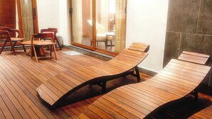 A wooden deck with lounge chairs and a table, a sliding glass door, and a view of the interior. - HF Pool Resorto (Chennai)
