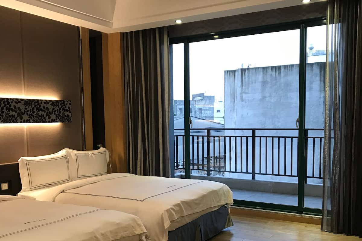 Ein Hotelzimmer mit einem großen Bett, Blick auf die Stadt vom Balkon und modernem Design.