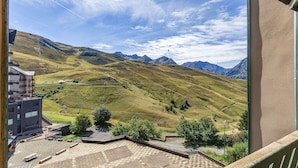 Une vue depuis un balcon donnant sur un paysage montagneux, avec un bâtiment au premier plan.
