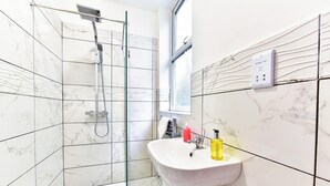A bathroom with a shower, a sink, and a window. - Drayton Green Road (London)