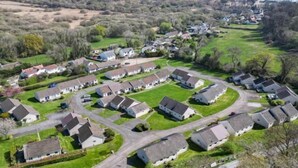Een woonwijk met huizen in een rasterpatroon, omringd door groen en een waterpartij op de achtergrond.