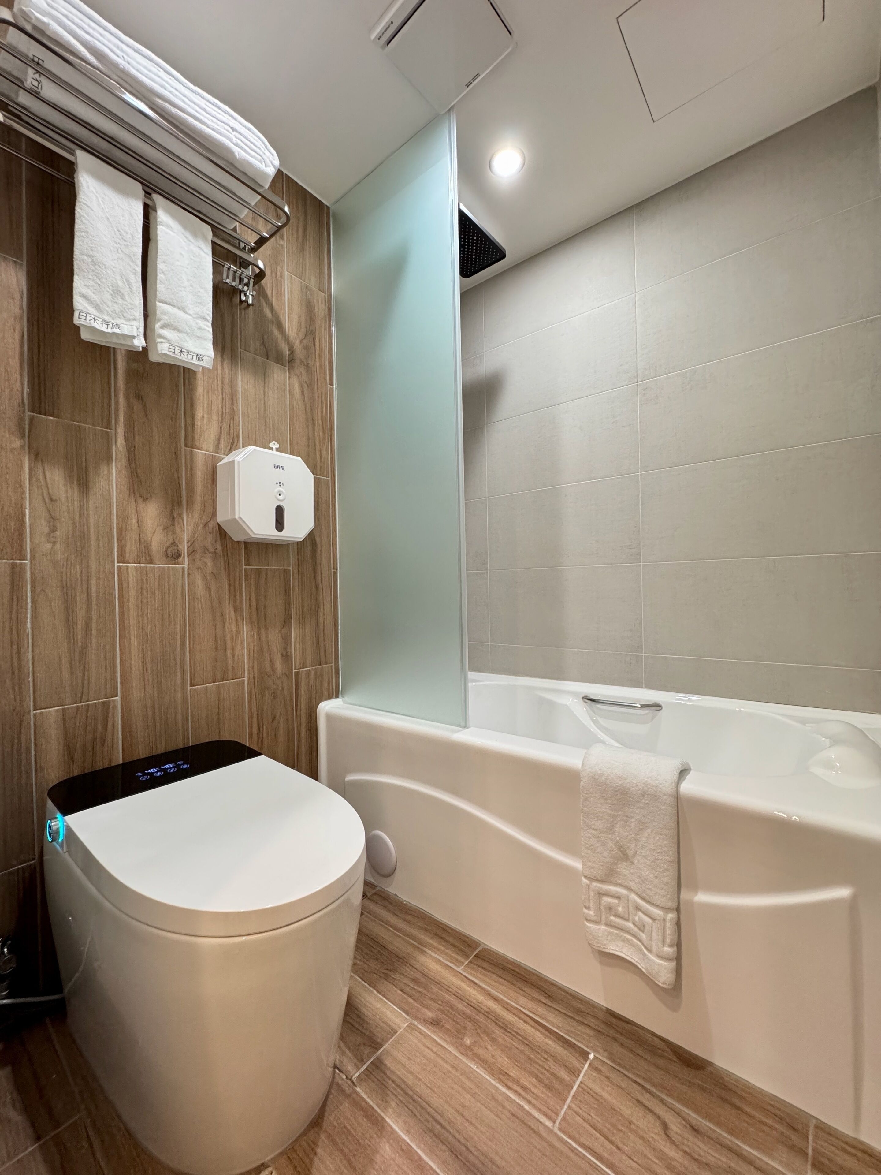 A modern bathroom with a toilet, a glass shower enclosure, and a bathtub.