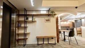 A modern interior with a wooden bench, shelves, and a dining area with chairs and tables. - Zuum Inn (Taipei)