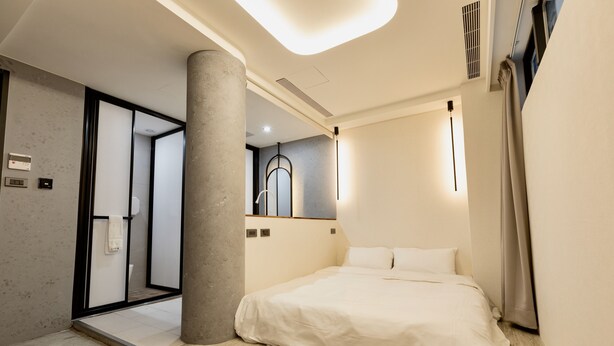 A modern hotel room with a large bed, a bathroom with a glass door, and a visible shower area. - Zuum Inn (Taipei)