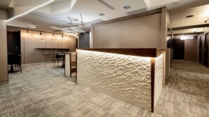 A modern reception area with a textured counter, a bar, and a seating area with chairs. - Zuum Inn (Taipei)