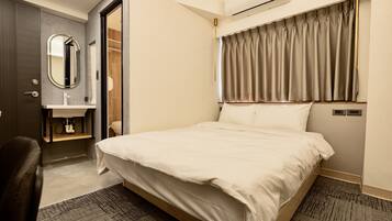 Quarto de hotel com cama, banheiro com espelho e janela com cortinas.