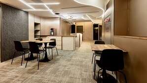 A modern hotel lobby with a central seating area, a reception desk, and a wall-mounted sign. - Zuum Inn (Taipei)