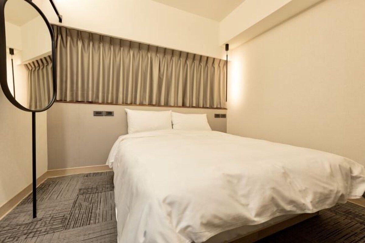 A hotel room with a large bed, a mirror, and a curtain headboard.