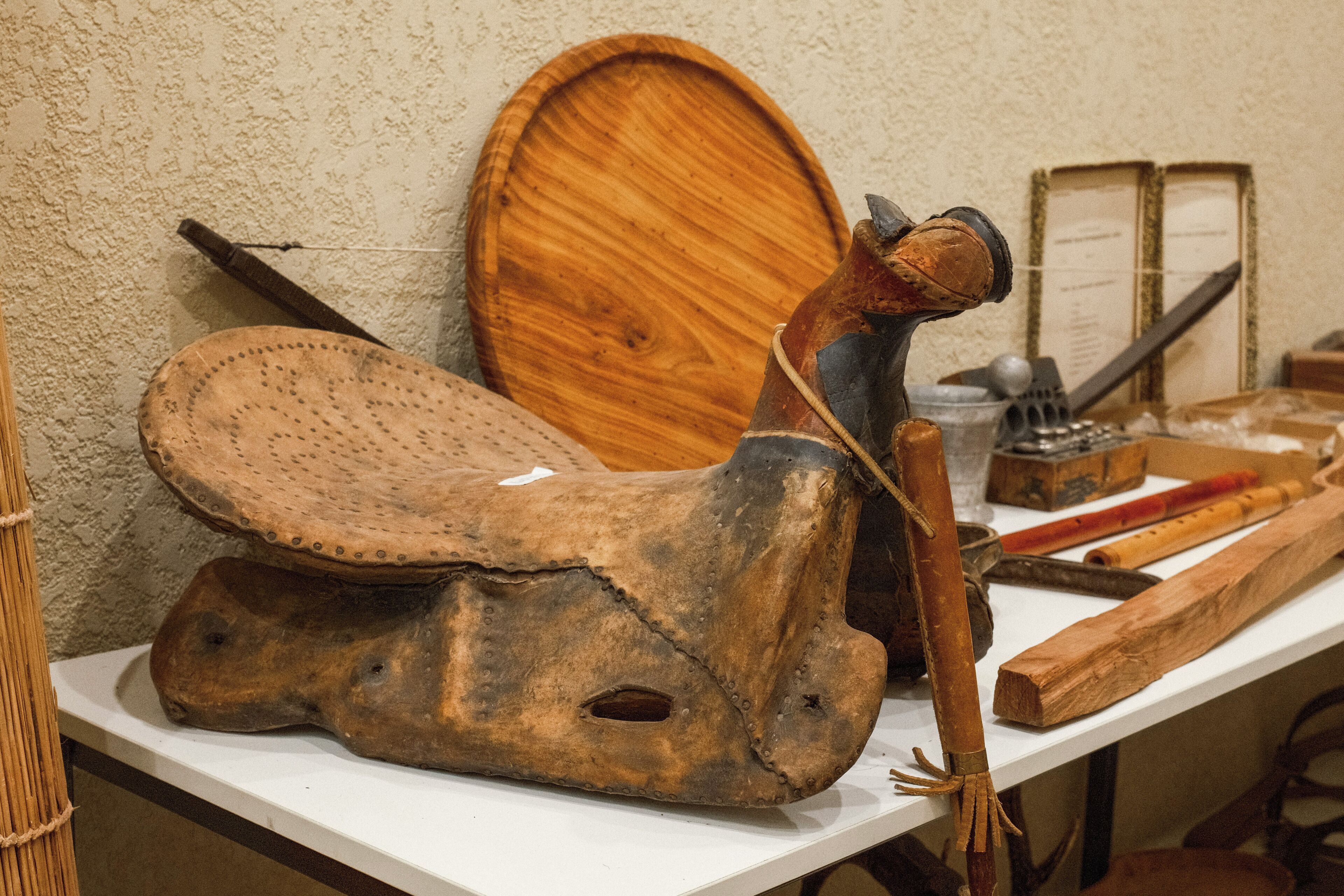 A table with a wooden object, possibly a tool, and a leather item.