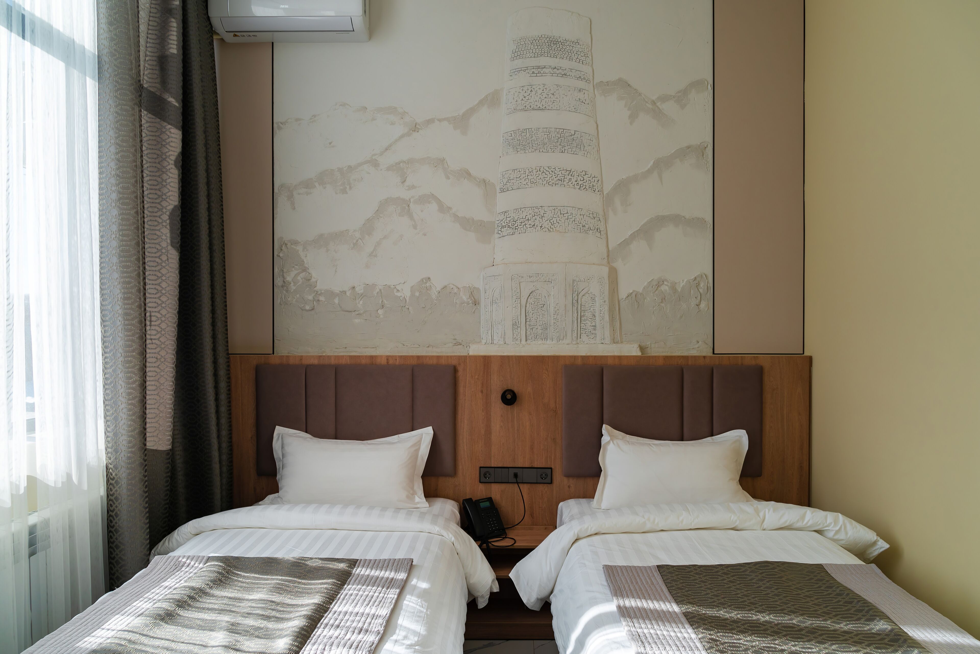 Une chambre d’hôtel avec deux lits, une grande œuvre d’art accrochée au mur et un téléphone.