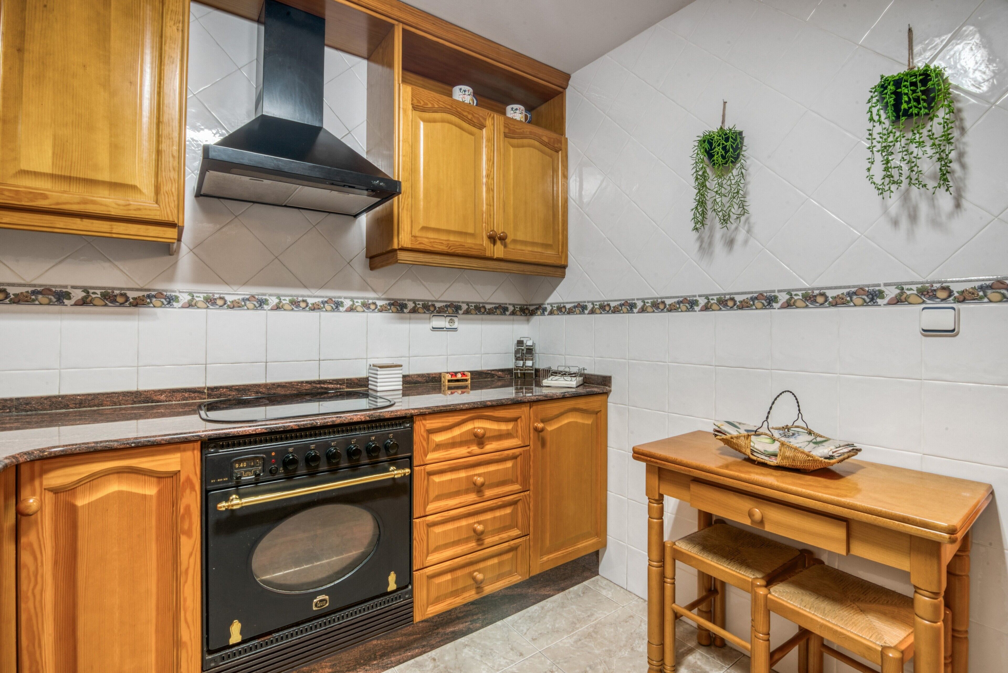 Una cocina con armarios de madera, una estufa y una pequeña mesa de madera con una cesta.