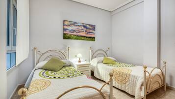 Una camera da letto con due letti, un comodino, una lampada e un quadro appeso al muro.