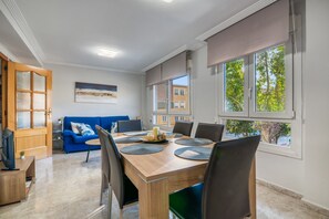 Un comedor con una mesa de madera, sillas negras y un sofá azul.
