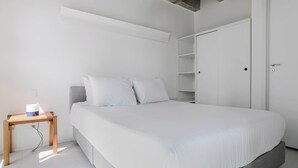 Un dormitorio minimalista con una cama grande, una mesita de noche y un armario.