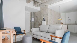 Una sala moderna con un sofá, sillas, una mesa de centro y un televisor.