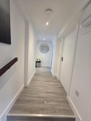 A narrow hallway with a wooden floor, white walls, and a door at the end. - Duffus Nights (Duffus)