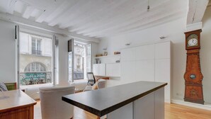 Une cuisine moderne dotée d’un îlot central, de meubles blancs et d’une grande fenêtre donnant sur un balcon.