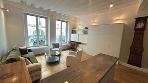 Un salon comprenant un canapé, des fauteuils, une table basse, une table en bois, un bureau et une armoire.