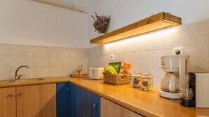 A kitchen with a wooden countertop, a coffee maker, a toaster, and a basket of bananas.