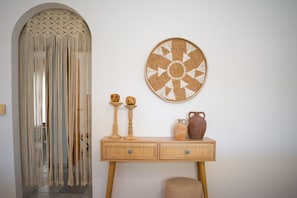 Ein Zimmer mit Wandbehängen aus Makramee, einer gewebten Wandkunst und einem Holzkonsole mit Schubladen sowie einem kleinen Hocker.