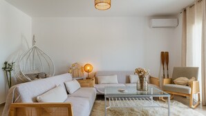 A modern living room with a sofa, a glass coffee table, a hanging chair, and a lamp.