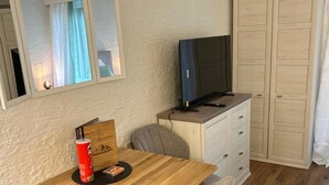 A small, cozy room with a wooden dining table, two grey chairs, a television on a cabinet, and a wardrobe. - Studio "Andys Edelweiss" in Leutasch (Leutasch)