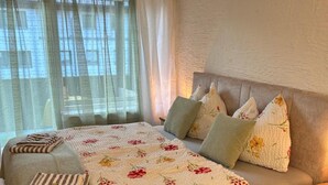 A bed with a floral bedspread, multiple pillows, and a striped throw blanket. - Studio "Andys Edelweiss" in Leutasch (Leutasch)