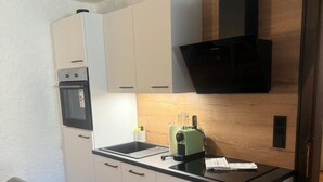 Cocina compacta con horno integrado, microondas, pileta y tetera eléctrica verde.