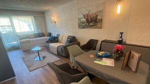 Una sala de estar con un conjunto de sofás, una mesa de centro, una mesita auxiliar con un jarrón y un libro, y un cuadro colgado en la pared de un toro.