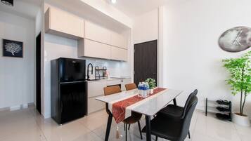 Una cocina moderna con armarios blancos, un refrigerador negro y un comedor con mesa y sillas.