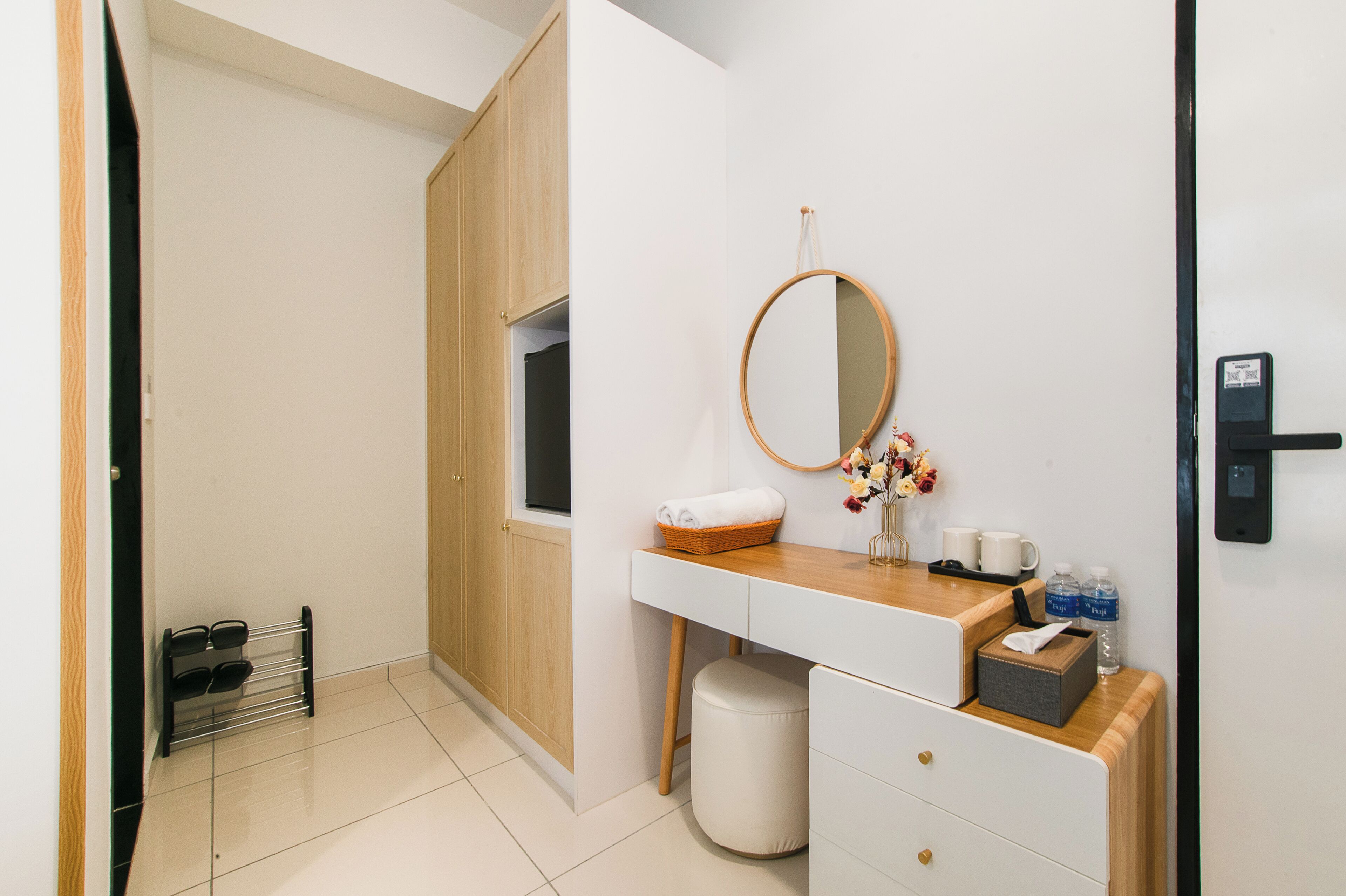 Un baño moderno con tocador de madera, un espejo redondo, un lavamanos pequeño y un inodoro.