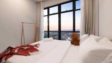 A hotel room with a large window, a bed, a teddy bear, and a wooden hanger.