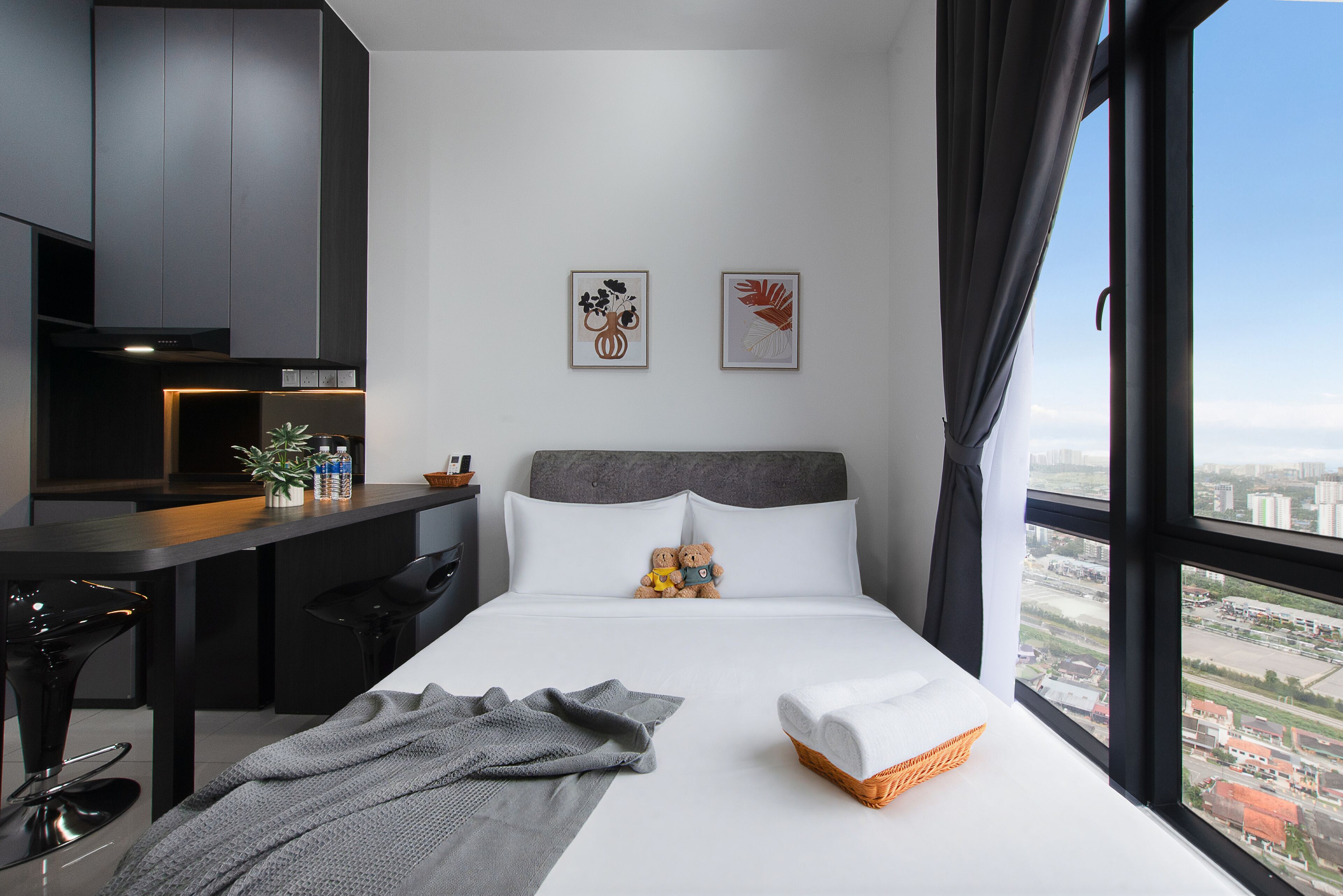 A modern hotel room with a bed, a desk, and a view of the city.
