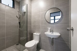 A modern bathroom with a glass-enclosed shower, a toilet, and a sink with a mirror above it.