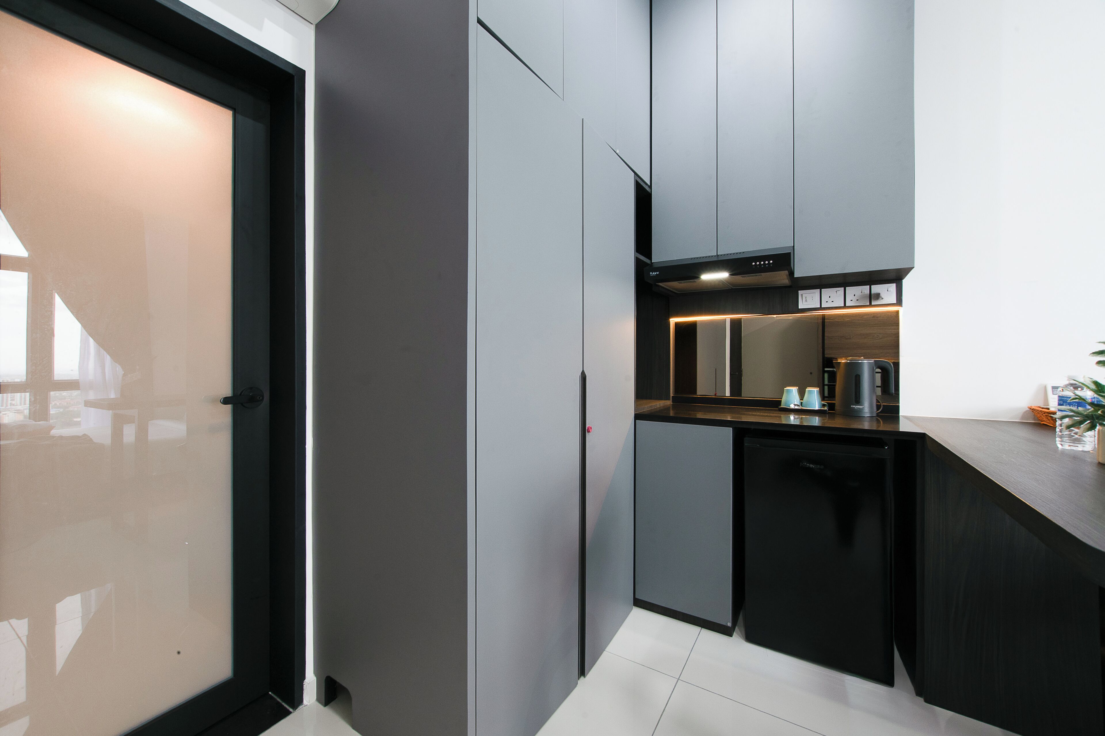A modern kitchen with grey cabinets, a black dishwasher, and a wooden countertop.