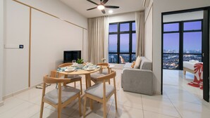 A modern living room with a dining area, large windows with a city view, a ceiling fan, and a flat-screen TV. - Space Residency by A----Walk 100m to KSL (Johor Bahru)