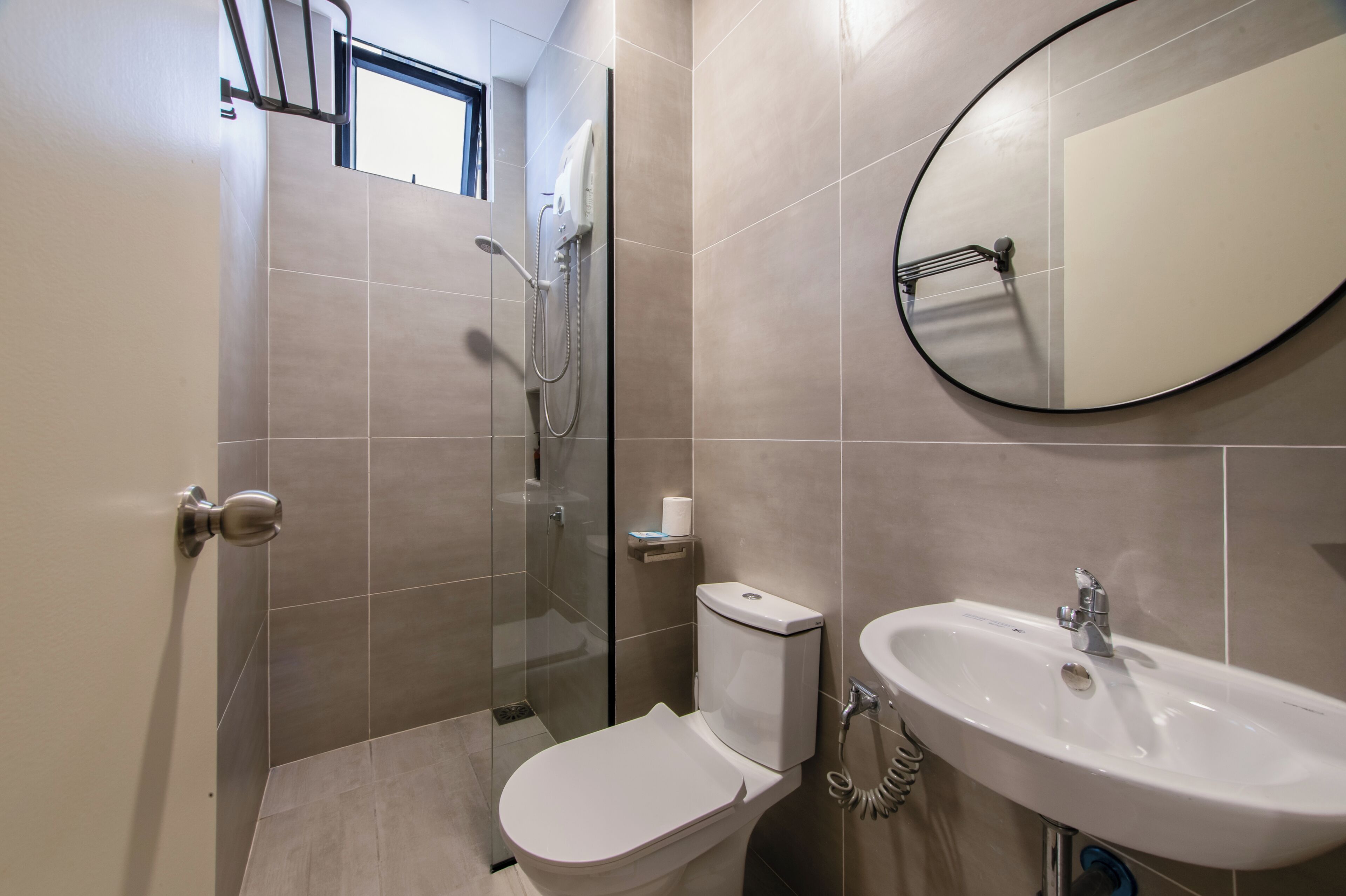 A modern bathroom with a toilet, shower, and sink.