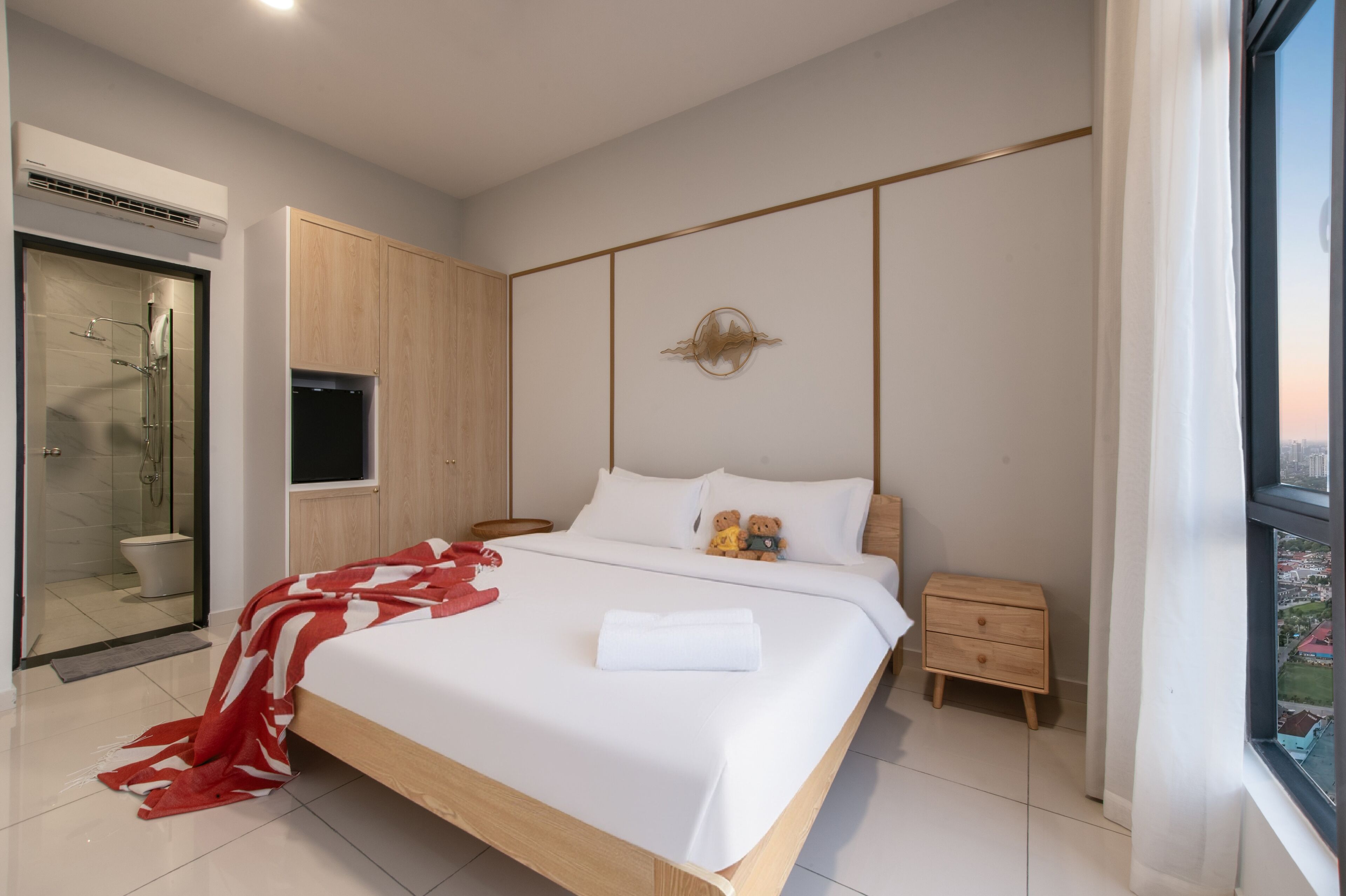 Una habitación de hotel moderna con una cama grande, una mesita de noche, un armario y una zona de ducha.