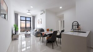 A modern, well-lit living room with a large window, a sofa, a dining table with chairs, and a kitchen area with a sink and countertop. - Space Residency by A----Walk 100m to KSL (Johor Bahru)
