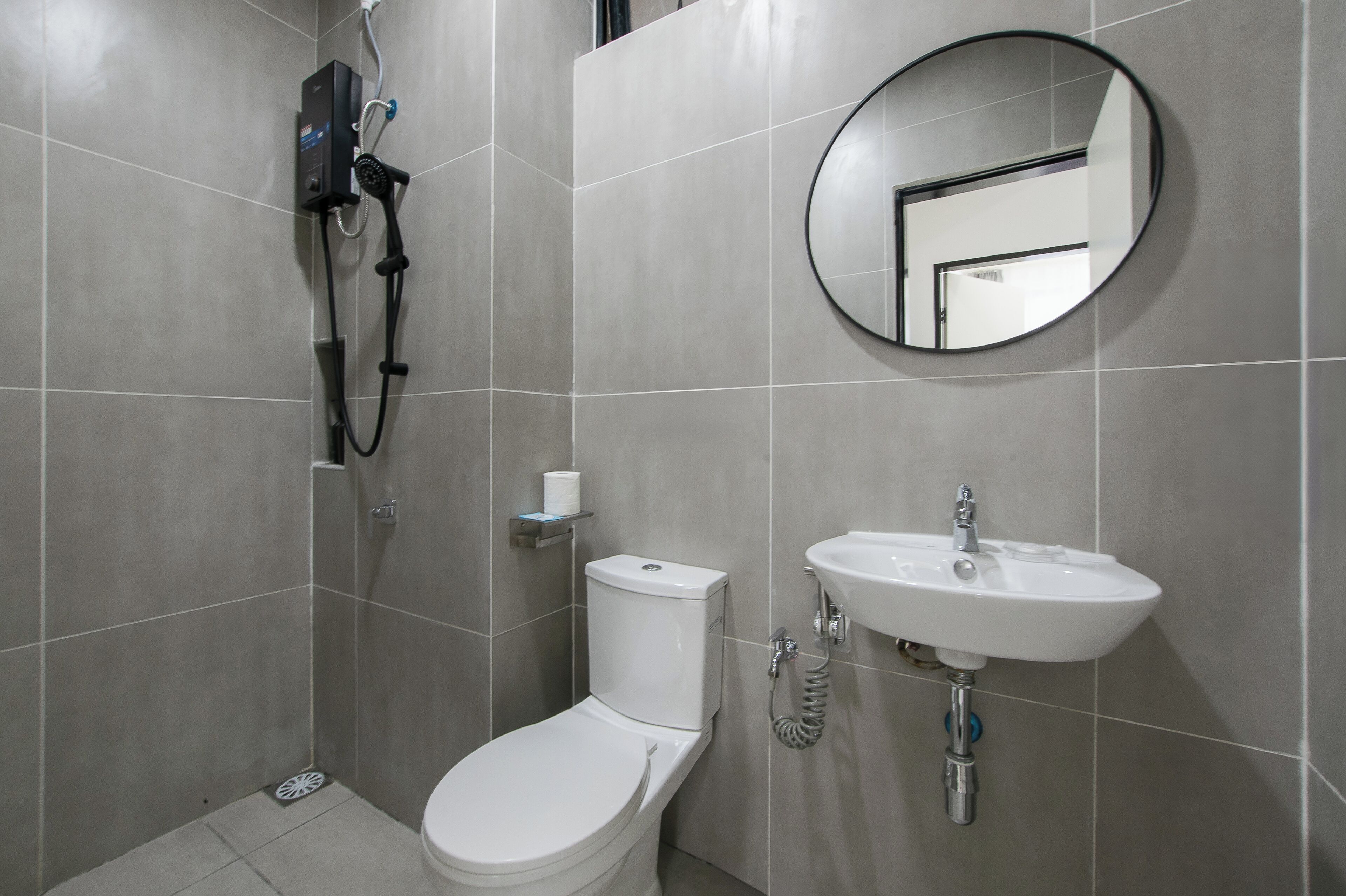 A bathroom with a toilet, a sink, a shower, and a mirror.