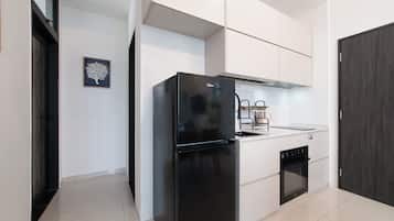 Una cocina moderna con armarios blancos, un refrigerador negro y un horno empotrado.