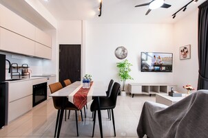 Una sala moderna con comedor, cocina y televisor montado en la pared.