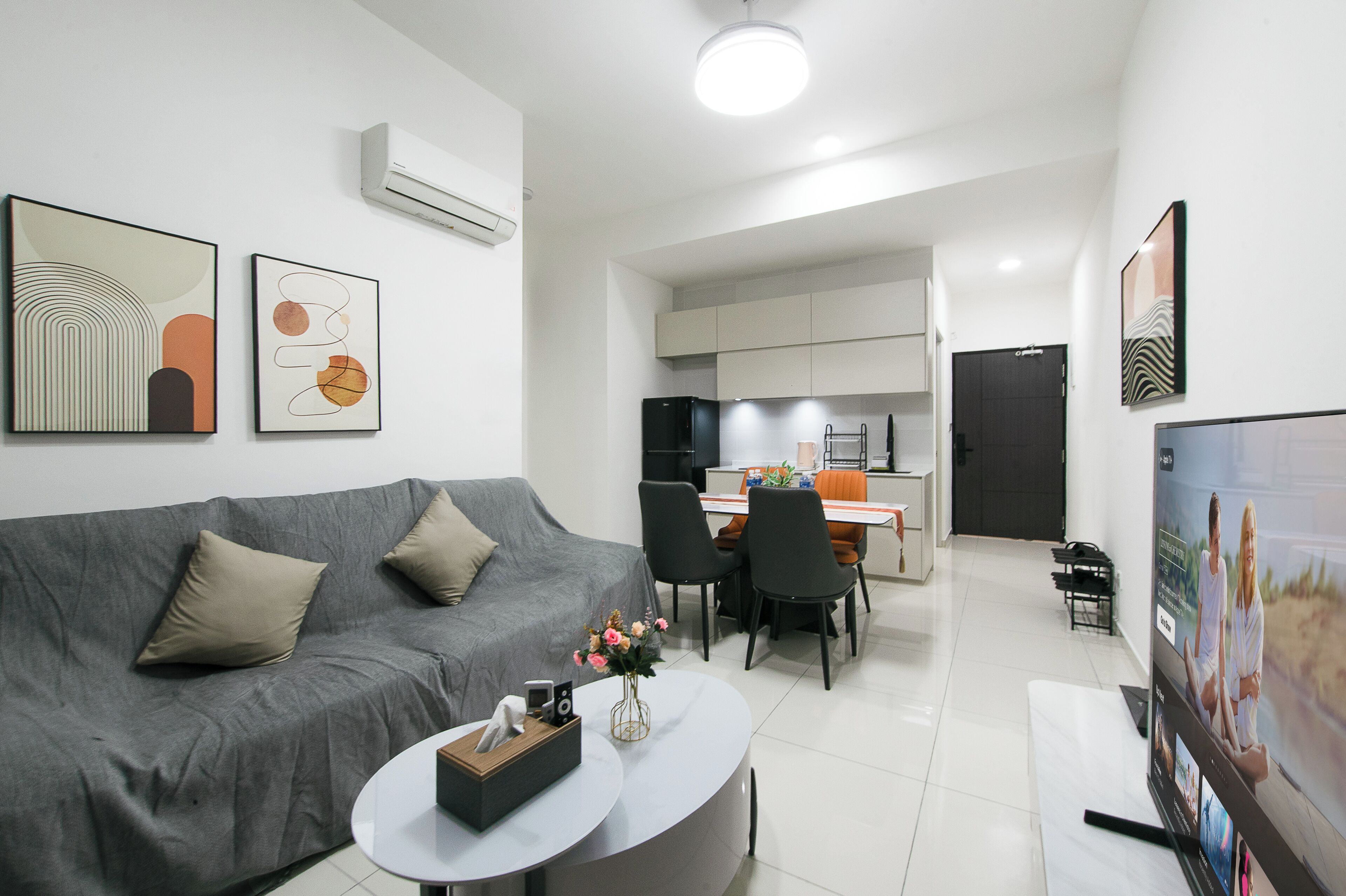 A modern living room with a grey sofa, a coffee table, and artwork on the walls.