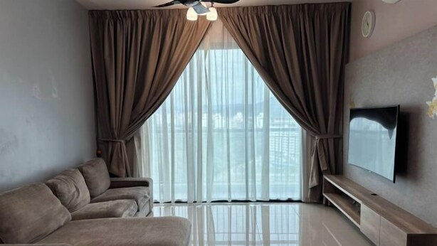 A modern living room with a sofa set, a flat-screen TV, and a large window with sheer curtains.