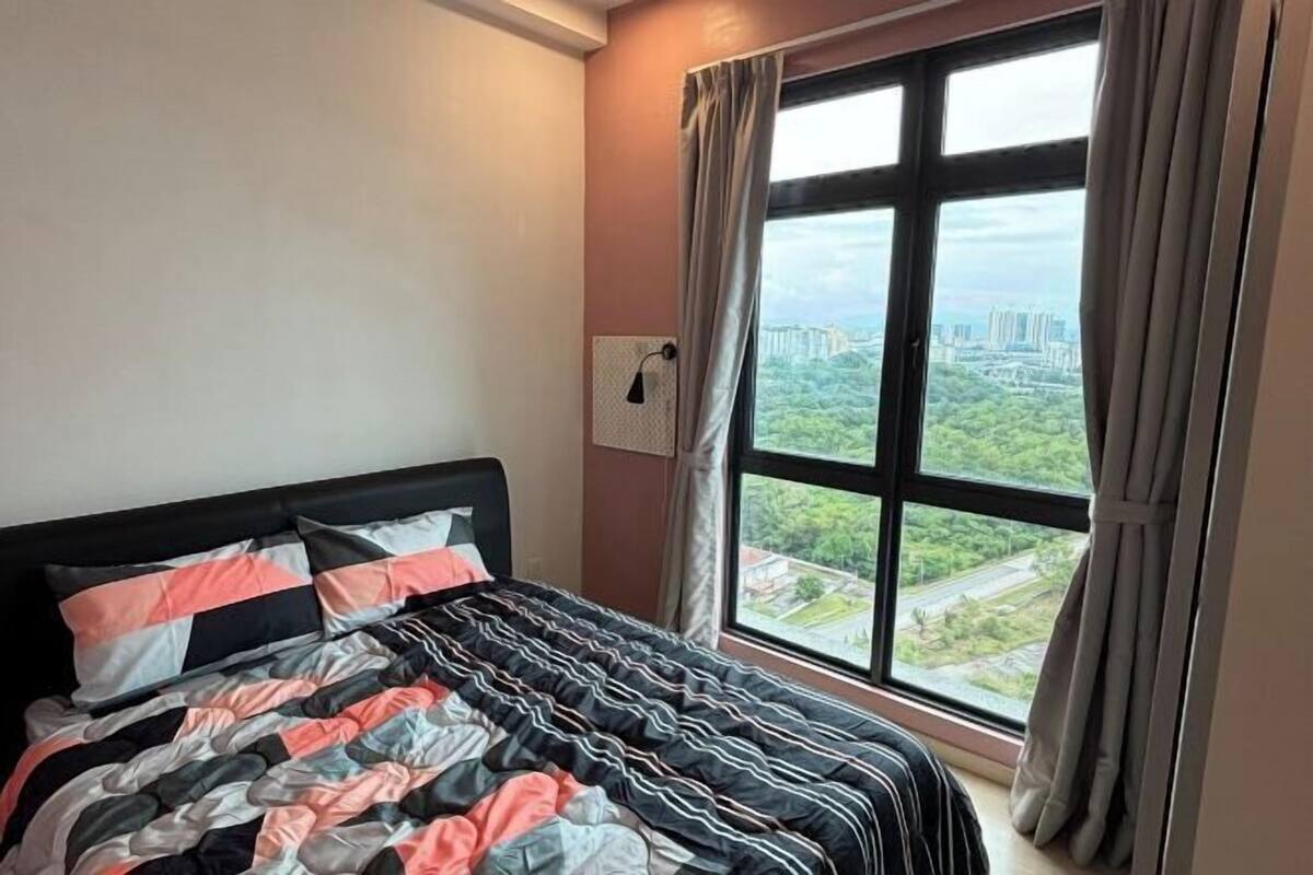 Ein Schlafzimmer mit einem Bett, einem Fenster mit Vorhängen und Blick auf eine Stadtlandschaft.