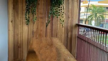 A wooden bench on a balcony with vertical wooden paneling and hanging plants.