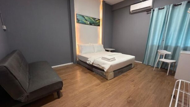 Une chambre à coucher comprenant un lit, une chaise, une petite table et un appareil de climatisation.