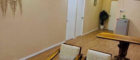 A hallway with two upholstered chairs, a wooden bench, and a door.