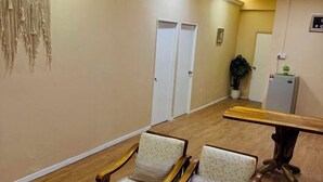 Un couloir avec deux chaises en bois, une table en bois, une porte blanche et une plante en pot.