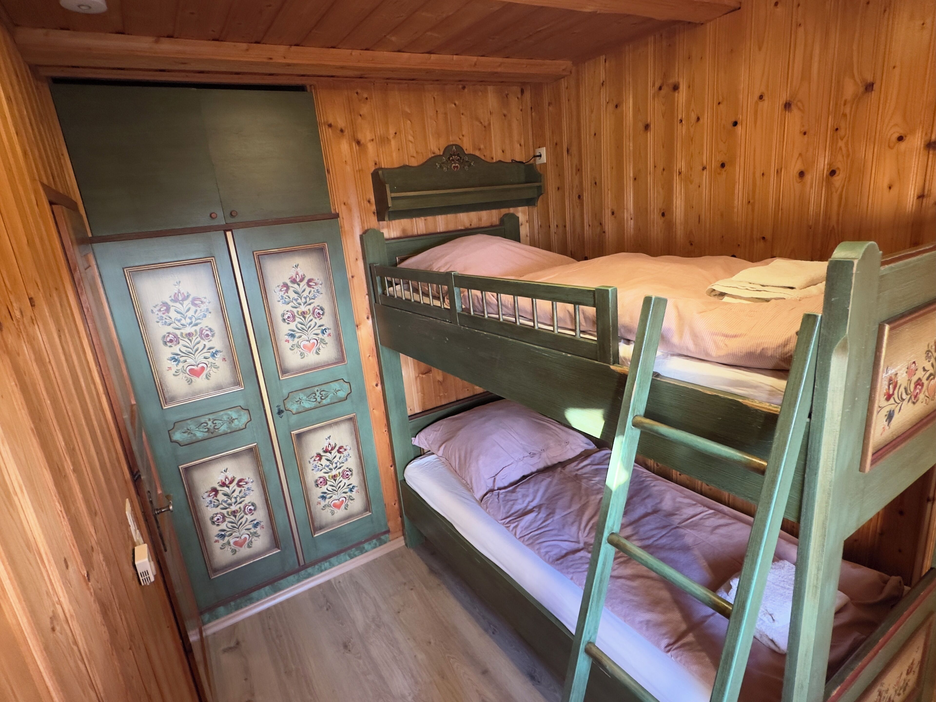 A wooden bunk bed with a decorative cabinet and a ladder.
